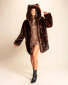 A Woman wearing a Spirit Hoods brown fur free fur coat with wolf ears on a beige background. SpiritHoods Made to Order brown wolf fake fur jacket with hood and ears, custom made fake fur coats 