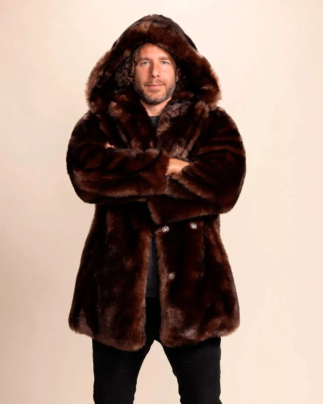 SpiritHoods Men's Hooded Faux Fur Coat in Brown Wolf. Vegan fake fur parka jacket for festivals, fall/winter layering. Model is facing the camera smiling with his arms folded infront of him, with the oversized hood up.