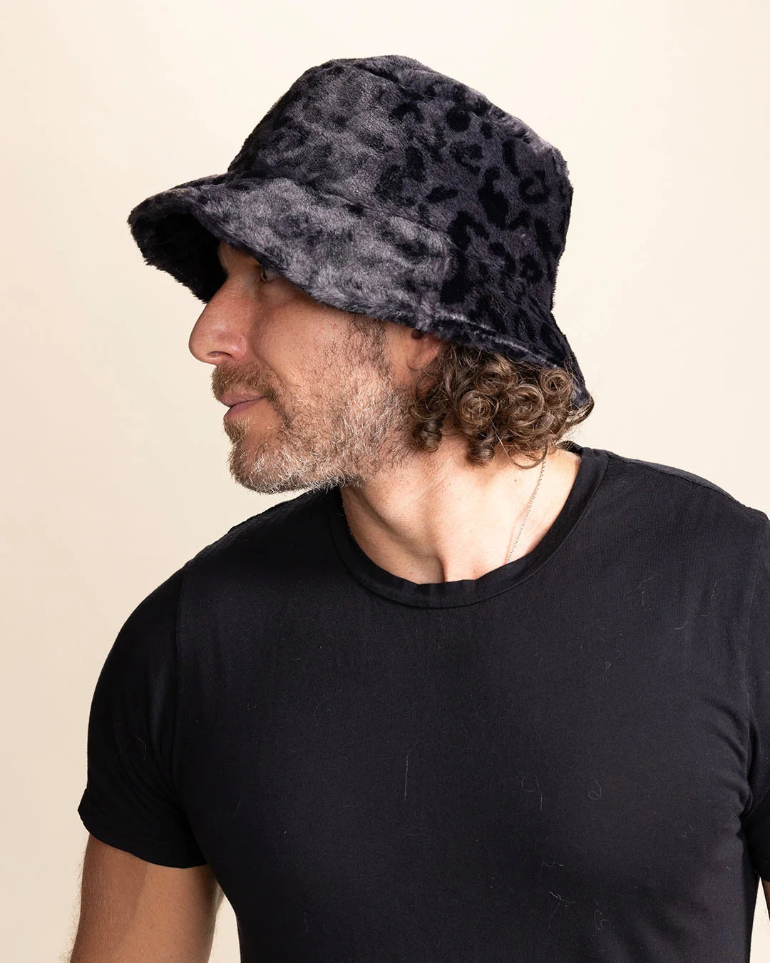 Man wearing a fuzzy slate grey leopard print on a black bucket hat against a plain background