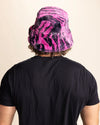 Person wearing a black t-shirt and a pink and black tiger patterned fuzzy bucket hat on a beige background