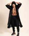 Man wearing a black sequined kimono robe over a black outfit on a beige background