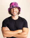 Man wearing a black t-shirt and pink bucket hat with black tiger stripes against a beige background