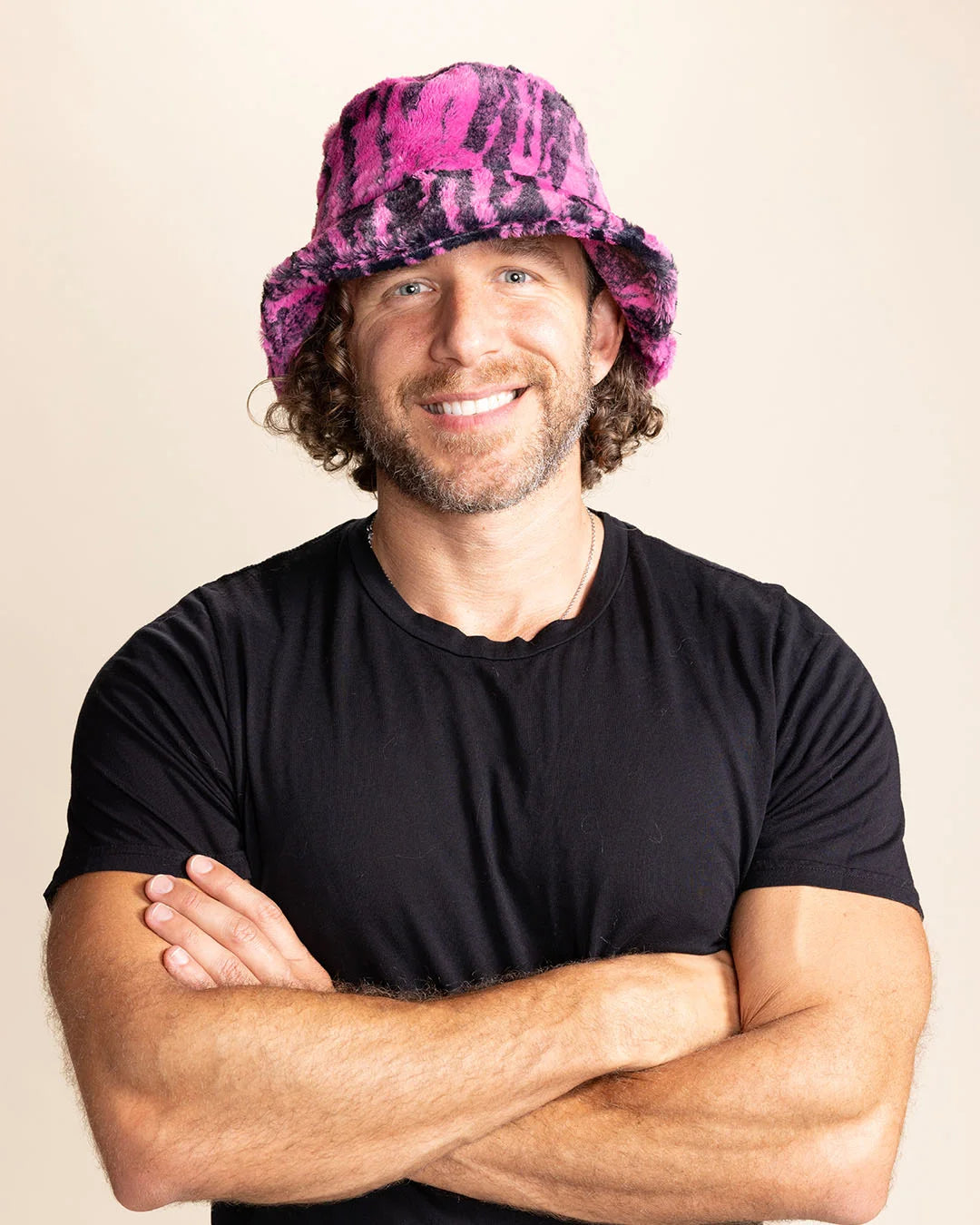 Man wearing a black t-shirt and pink bucket hat with black tiger stripes against a beige background
