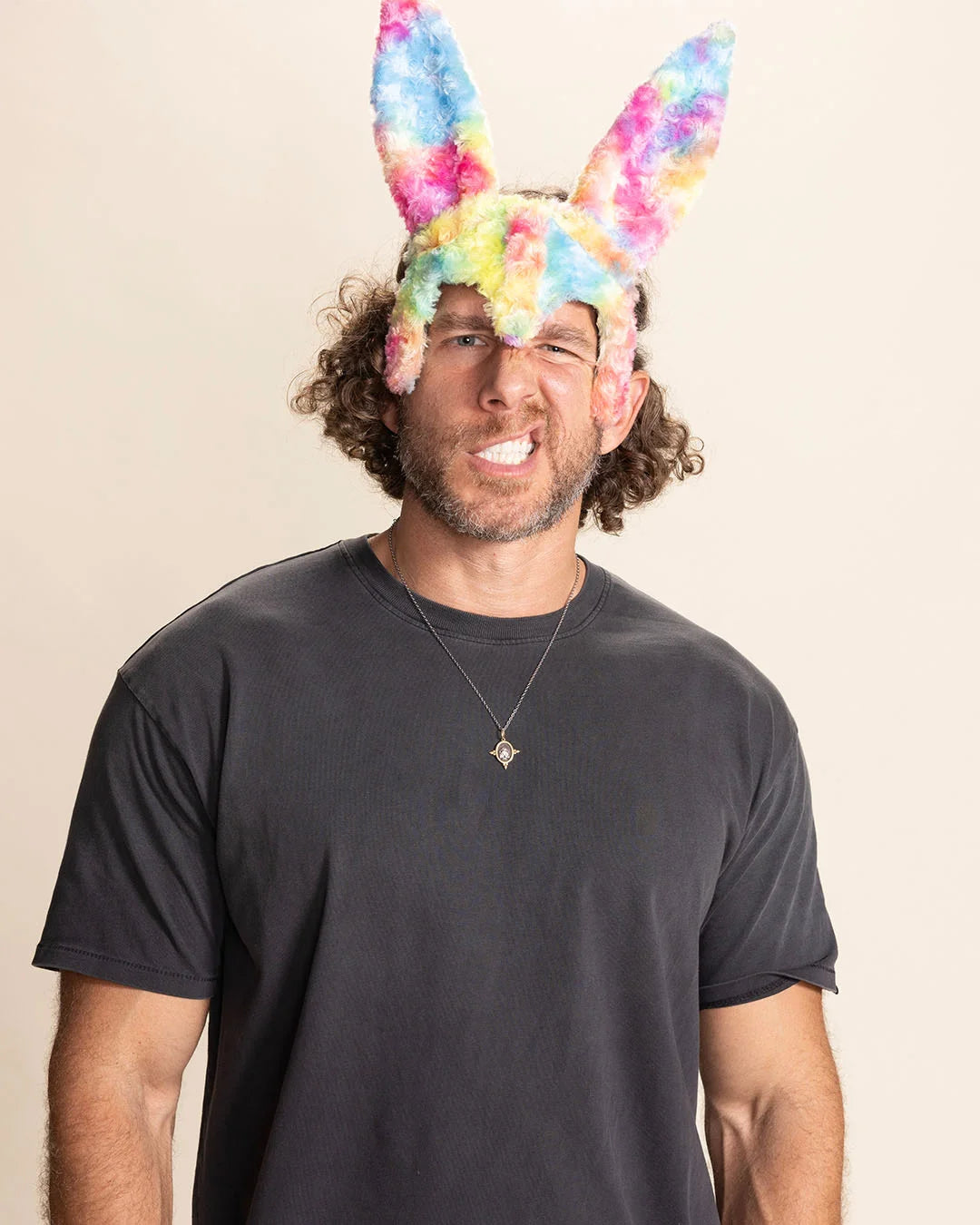 Man wearing a black t-shirt and colorful bunny ears against a beige background