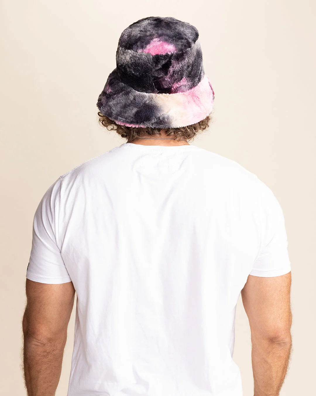 Person wearing a tie-dye bucket hat with pink and blue patterns on a beige background