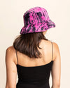 Person wearing a pink and black animal print bucket hat on a beige background