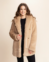 Woman wearing a beige Faux Fur Coat with large oversized collar being worn down, as she holds the front panel of the plush fake fur jacket and smiles at the camera. SpiritHoods 100% Fake Fur Fall Winter Collection of Coats for Women in Cougar.