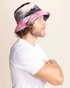 Person wearing a colorful bucket hat with pink and black patterns on a beige background