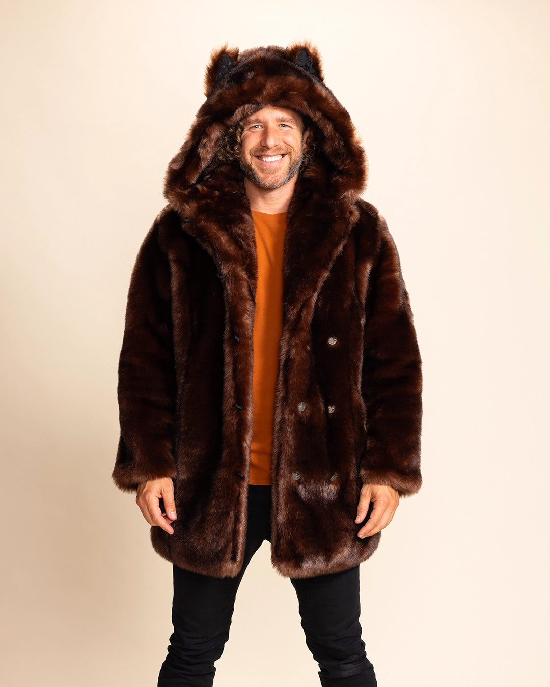A Man wearing a brown fur free fur coat with wolf ears on a beige background. SpiritHoods Classic Faux Fur Coat in Brown Wolf with oversized hood and ears - Made to order limited waste fall winter coat collection.