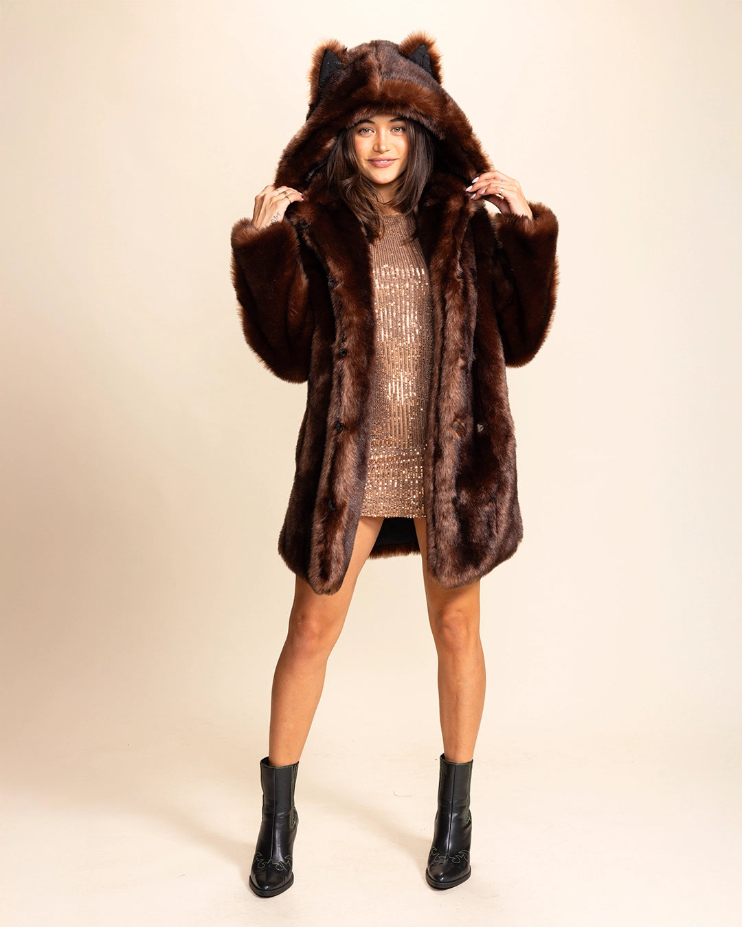 Woman wearing a brown wolf fake fur coat with cute wolf ears on a beige background. SpiritHoods 100% Fake Fur Brown Wolf Coat with Hood and Ears. Custom Made Fake Fur Jackets for Fall and Winter.