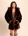 Top-rated SpiritHoods Womens Faux Fur Coat with hood and wolf buttons and model has her hands in the two front pockets. Brown fake fur jacket, cruelty-free and vegan fashion.
