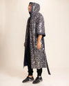 Person wearing a long, patterned leopard sequin print kimono-robe on a plain background