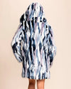Back view of SpiritHoods Women's Hooded Faux Fur Coat in multicolor icy blue, lavender, purple, snow white, and midnight navy with oversized hood up and hands in the two outer pockets.