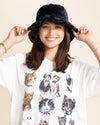 Woman wearing a fuzzy black bucket hat and a white t-shirt with cat illustrations.