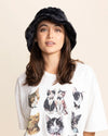 Girl wearing a black fur bucket hat and a white t-shirt with cat prints on a beige background