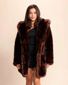 Model with shoulder length brown hair smiling at the camera wearing SpiritHoods luxe collector edition deep chocolate brown faux fur coat with the hood down.