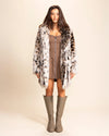 Woman wearing a cheetah print fake fur coat with the collar down, and knee-high boots on a beige background. SpiritHoods Made to Order Plush Faux Fur Jackets