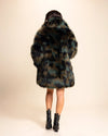 A Woman wearing a plush fake fur coat with tie-dye style greens, browns and black throughout on a beige background. SpiritHoods Made To Order Fall Coats and Fake Fur Custom Made Jackets