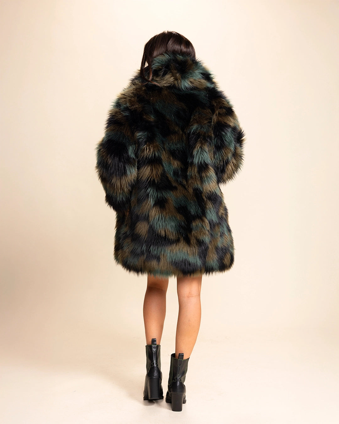 A Woman wearing a plush fake fur coat with tie-dye style greens, browns and black throughout on a beige background. SpiritHoods Made To Order Fall Coats and Fake Fur Custom Made Jackets