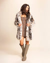 Woman wearing a SpiritHoods Made To Order Little Cheetah fake fur coat and knee-high boots on a beige background