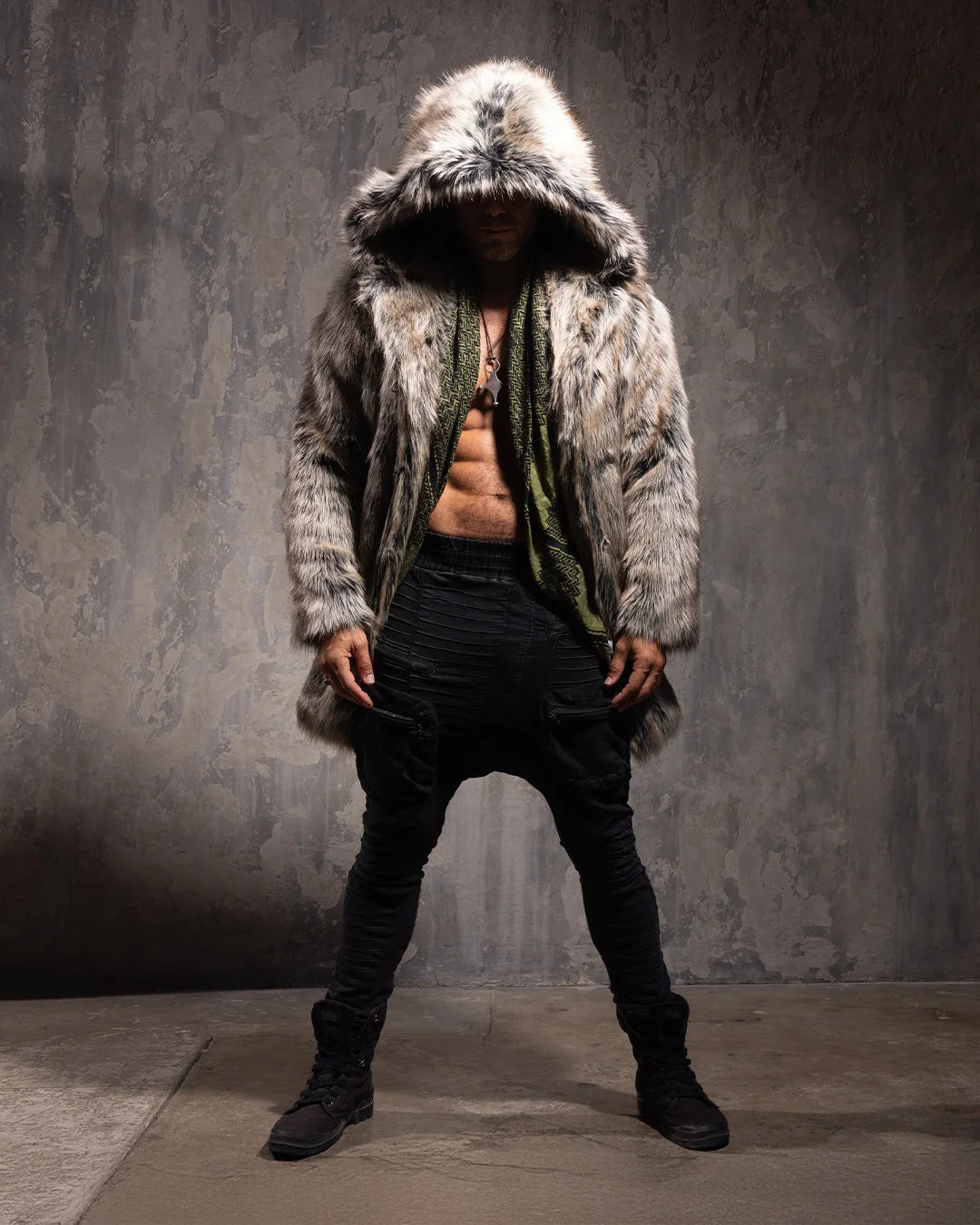 Man wearing a Hooded Men's Faux Fur Coat in Grey Wolf with the hood up as he looks down, against a textured gray background