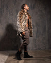 Man wearing a leopard print faux fur coat against a textured gray wall.