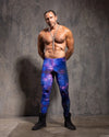 Man wearing galaxy-velvet leggings against a textured gray wall.