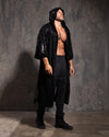 Man wearing a black hooded kimono with sequin black snakeskin pattern against a textured gray wall