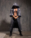 Man wearing a silver and gold leopard print sequined hooded kimono against a textured wall.