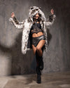 Woman dancing wearing SpiritHoods cruelty-free Little Cheetah Classic Fake Fur Coat, against a gray wall