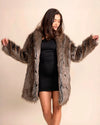 Women's Luxe Faux Fur Coat in brown and grey wolf print. Luxe vegan festival jacket over a black dress against a plain background