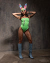 Woman wearing a festival outfit; colorful bunny ears mask, and blue boots against a textured gray background