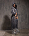 Woman wearing a silver sequin blue denim leopard print kimono with platform shoes against a textured gray wall.