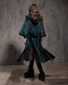 Woman wearing a dark green tiger print textured velvet kimono with a hood against a gray textured wall.