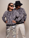 Two people wearing matching patterned sweaters and pants against a neutral background