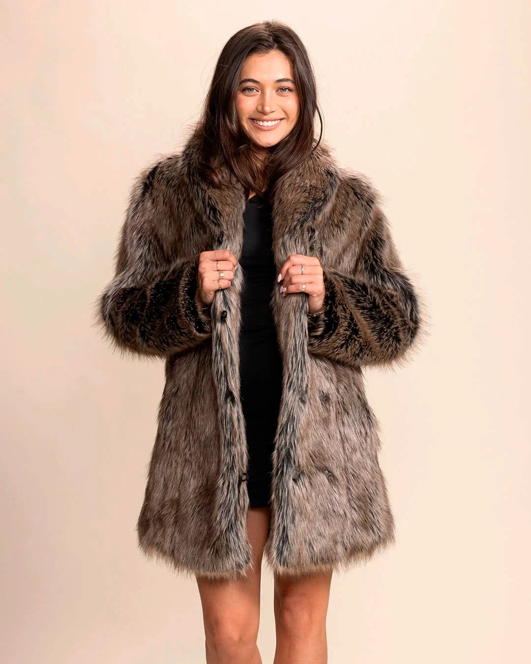 Woman smiling wearing a Dire Wolf grey fake fur parka coat against a plain background
