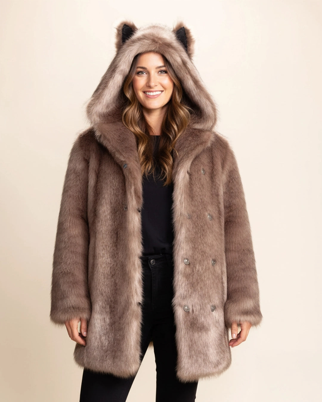 Woman wearing a SpiritHoods Fall Winter Classic brown faux fur coat with an oversized hood and wolf ears on a beige background. SpiritHoods Fall/Winter Faux Fur Animal Inspired Jackets, PETA-Approved Vegan Fashion Brand.