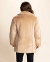 Beige fake fur coat worn by a woman facing away from the camera showing the back part of the coat, shiny plush luxury fake fur that is a light-tan meets beige, inspired by the beautiful Cougar. SpiritHoods Fall Winter Collection of Vegan Fake Fur Coats and Faux Fur Jackets for Women