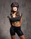 Woman wearing a Sequin Festival Captain's Hat with red and purple sequins in a black outfit with decorative elements against a textured gray background