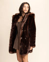 SpiritHoods top-rated faux fur coats for women. Model smiling, looking over her shoulder wearing the Women's Hooded Faux Fur Coat with wolf-face buttons down the front.