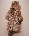 A woman facing away from the camera wearing SpiritHoods Leopard print faux fur coat with hood up and ears showing, on a plain background. SpiritHoods Custom Made Fake Fur Jackets - limited waste production