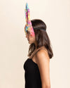 Woman wearing a colorful bunny mask with large tie-dye ears and headband against a beige background