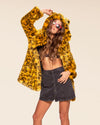 Bold streetwear style for women: a yellow cheetah faux fur jacket with a large hood and premium vegan materials.