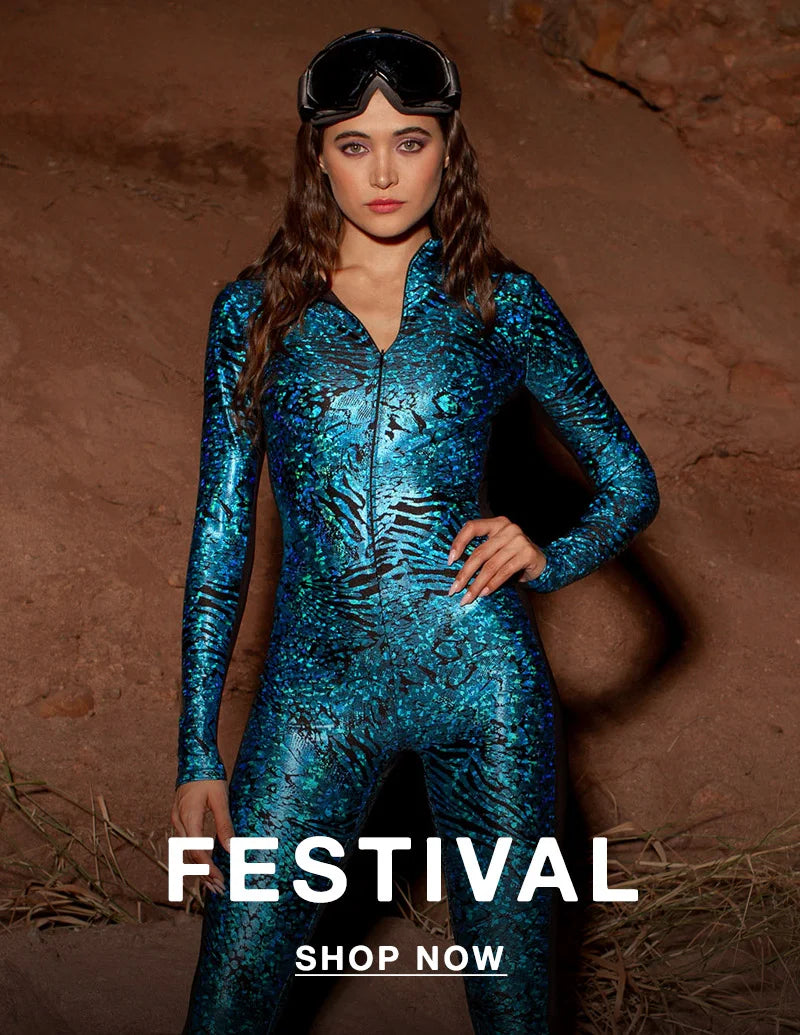 A woman stands confidently in front of a rocky, desert-like background wearing a shimmering, skintight blue and black bodysuit with an abstract animal print. She has long wavy hair and wears black goggles pushed up on her head. Bold white text at the bottom reads “FESTIVAL” with a “SHOP NOW” button underneath.