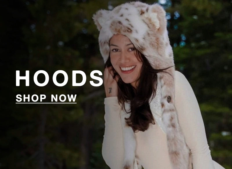 Woman wearing a fluffy hooded coat with text 'HOODS SHOP NOW' in a snowy outdoor setting