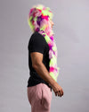 A man in profile wearing a vibrant neon pink, purple, and lime green faux fur hood and long scarf against a plain gray studio background.