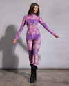 Woman standing in a pink tie-dye leopard full bodysuit with long sleeves and a mock neckline.