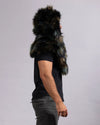 A man shown from the side wearing a dark faux fur hooded shawl over a black t-shirt and gray jeans, against a plain light gray background.