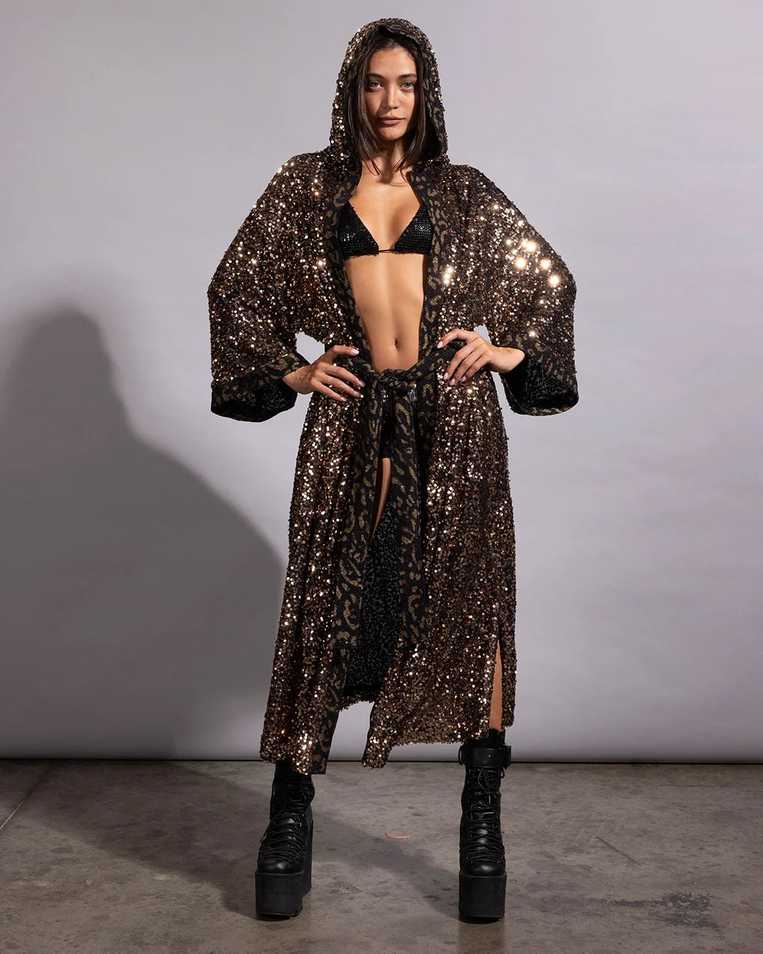 Woman smiling in a gold leopard sequin festival kimono with a deep hood and shimmering metallic pattern.