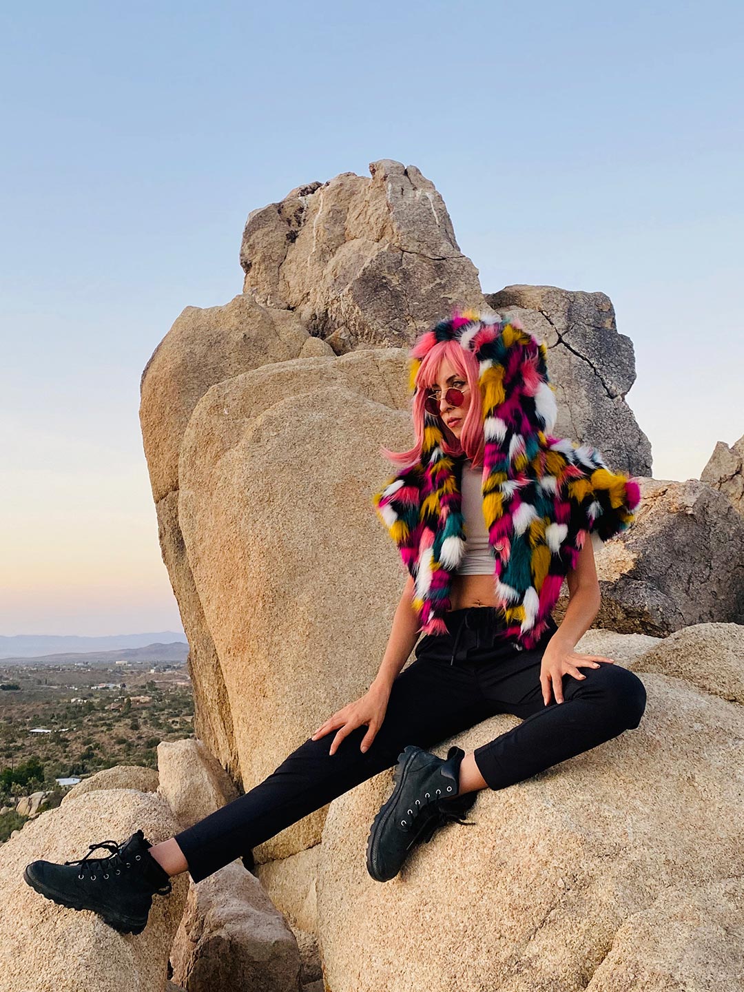 Rainbow Butterfly Hooded Faux Fur Shawl Worn By Woman Sitting on Rock